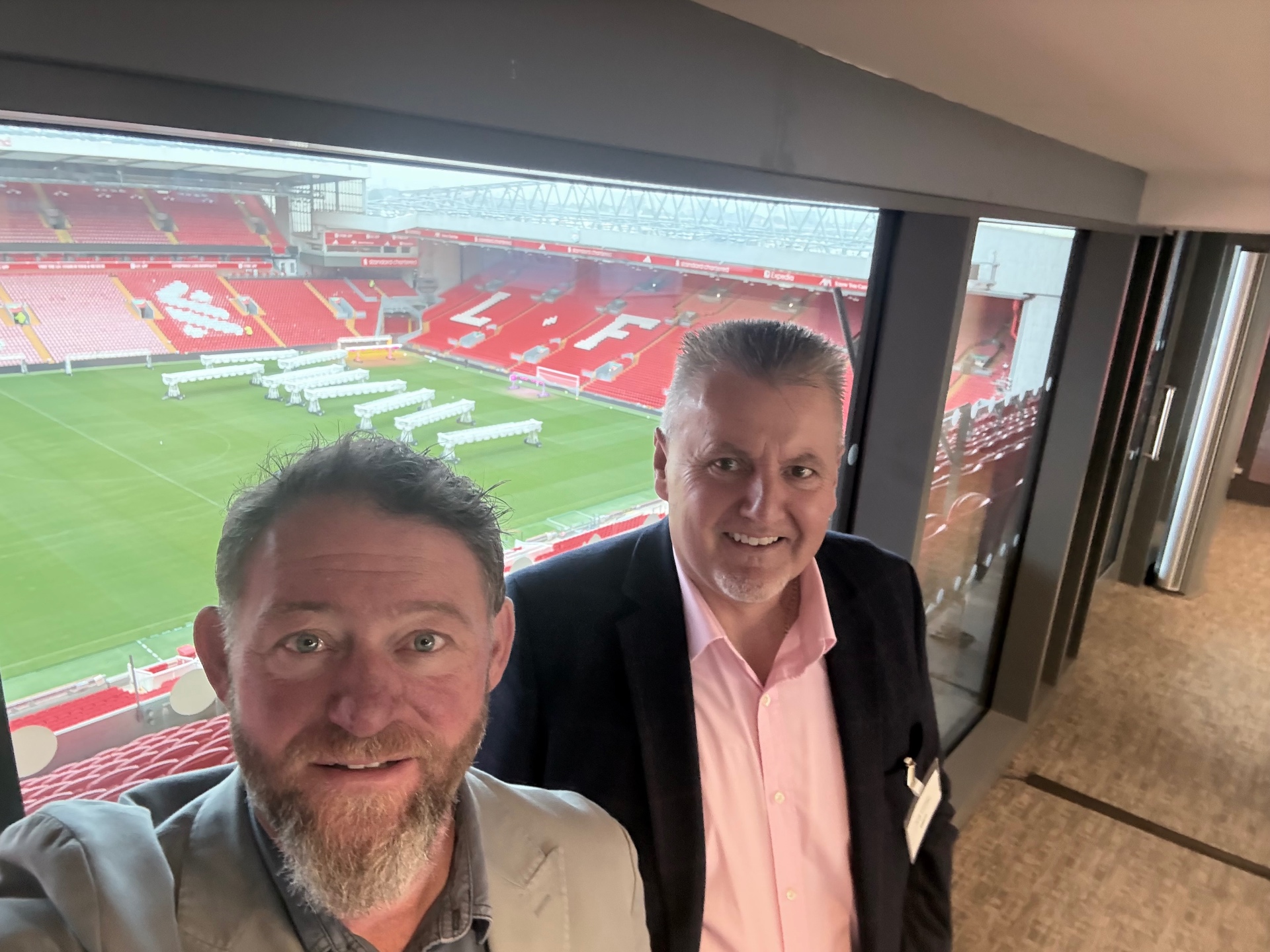 Stuart Maddocks and Andy Clemson in a stadium hospitality box overlooking the pitch at Liverpool FC