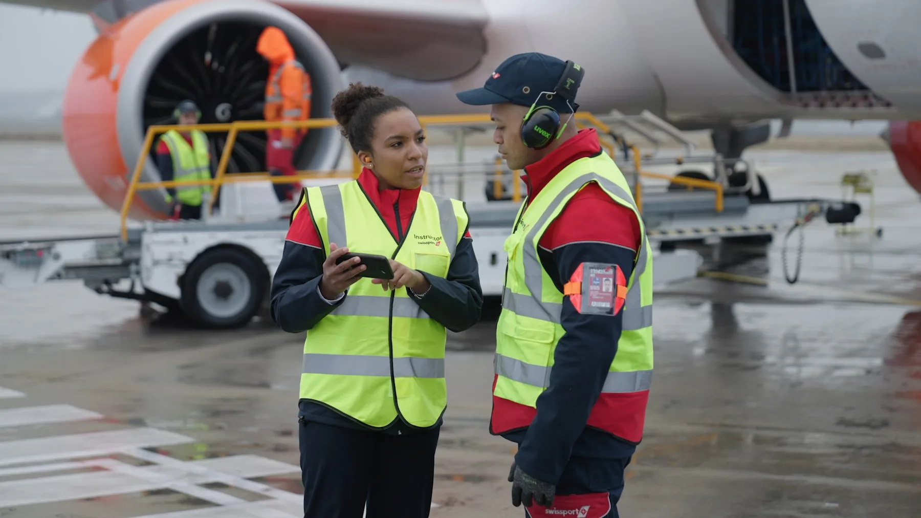 Two Swissport ground operations employees conferring beside an aircraft on the ramp